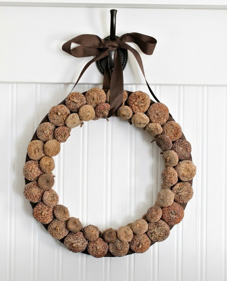 DIY acorn wreath made with layered acorn caps on a brown ribbon-wrapped wreath form